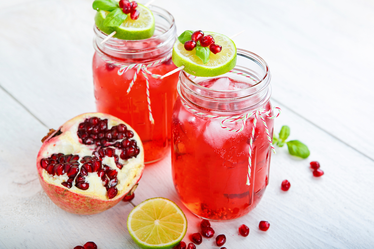 Two glasses with red pomegranate juice, lemon and mint.
