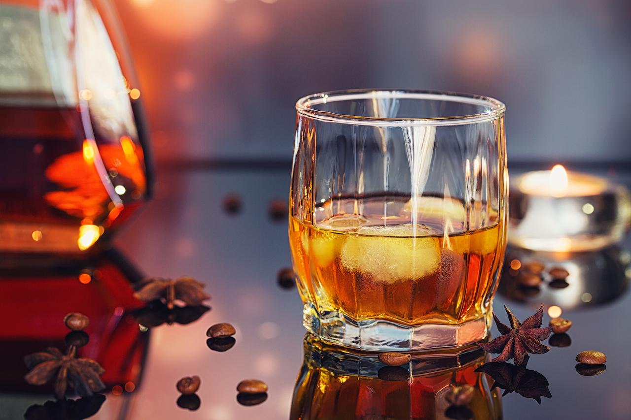 Cognac or liqueur, coffee beans and spices on a glass table.